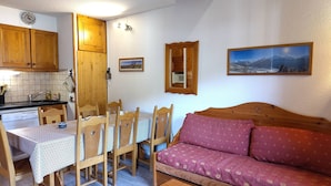 A cozy living room with wooden furniture, a dining table, and a sofa. - Duplex for 8, Quiet, Near Shuttle and Pool (Aussois)