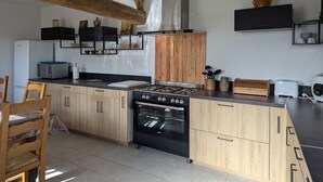 Une cuisine moderne avec des meubles en bois, un four encastré et une cuisinière à gaz.