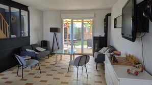 Un salon avec un canapé, des fauteuils, un téléviseur et une cheminée.