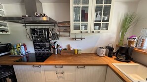 A kitchen with a wooden countertop, a built-in stove, a coffee maker, and a window with blinds. - Holiday home 100m from the beach for 4 people (La Croix-Valmer)