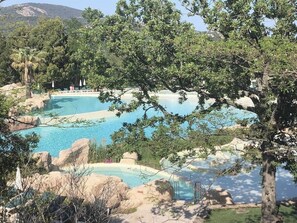 A pool area with multiple water features surrounded by trees and rocks. - The Terraces of the Gulf of Saint-Tropez, 1,600 m² water park, wave pool (Grimaud)