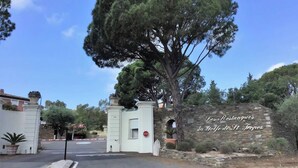 Une entrée fermée par un portail, avec un mur en pierre et une enseigne indiquant : « Les Restanques du Golf de l’Isle de Toros ».