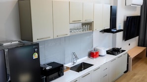 A modern kitchen with white cabinets, a black refrigerator, a microwave, a sink, and a stove. - Six elements pool villa khaokho (Khao Kho)