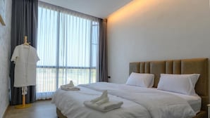 A neatly made bed with white linens and towels, a wooden headboard, and a window with sheer curtains. - Six elements pool villa khaokho (Khao Kho)