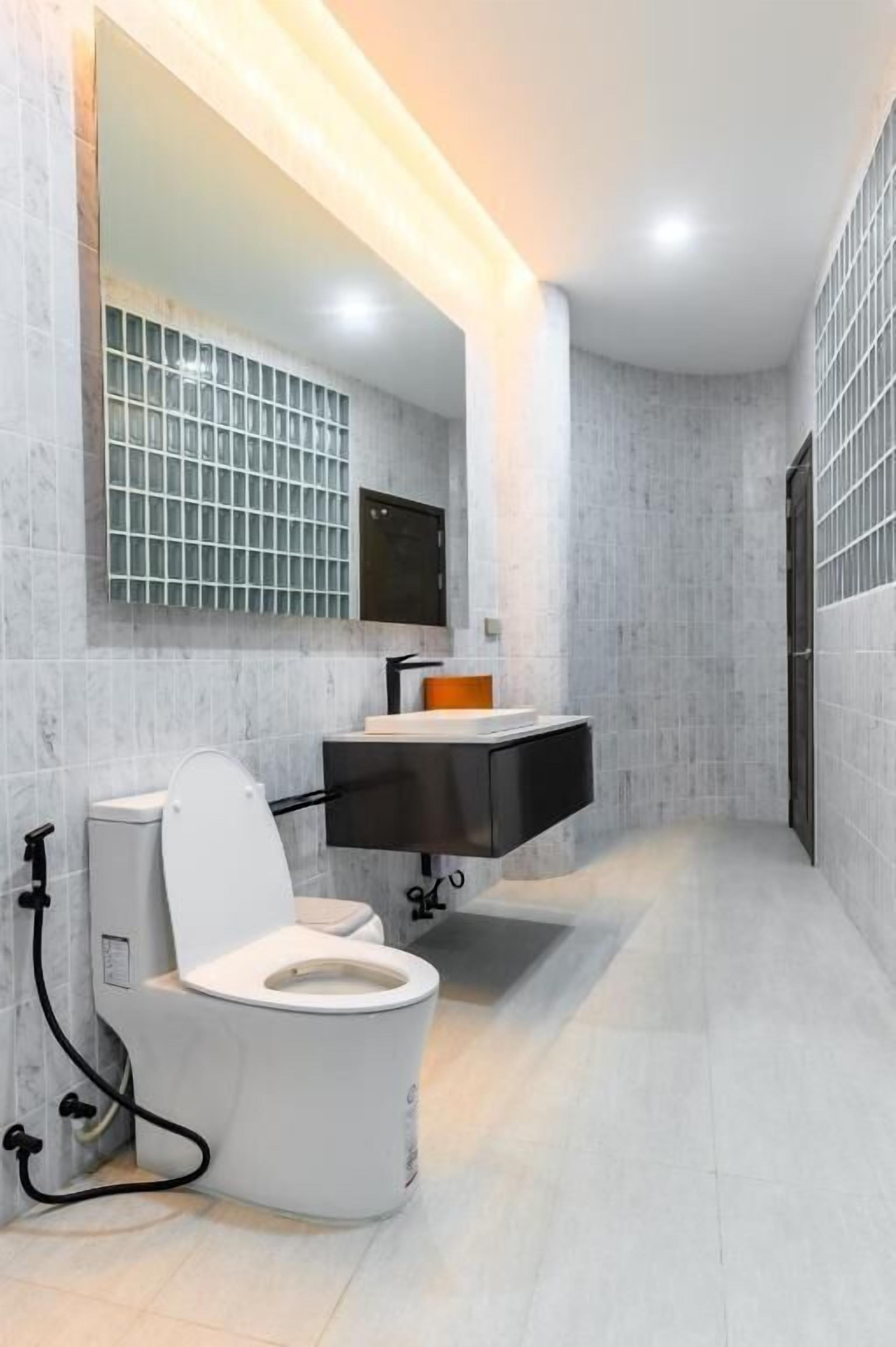 Une salle de bain moderne avec des toilettes, un lavabo et un miroir.