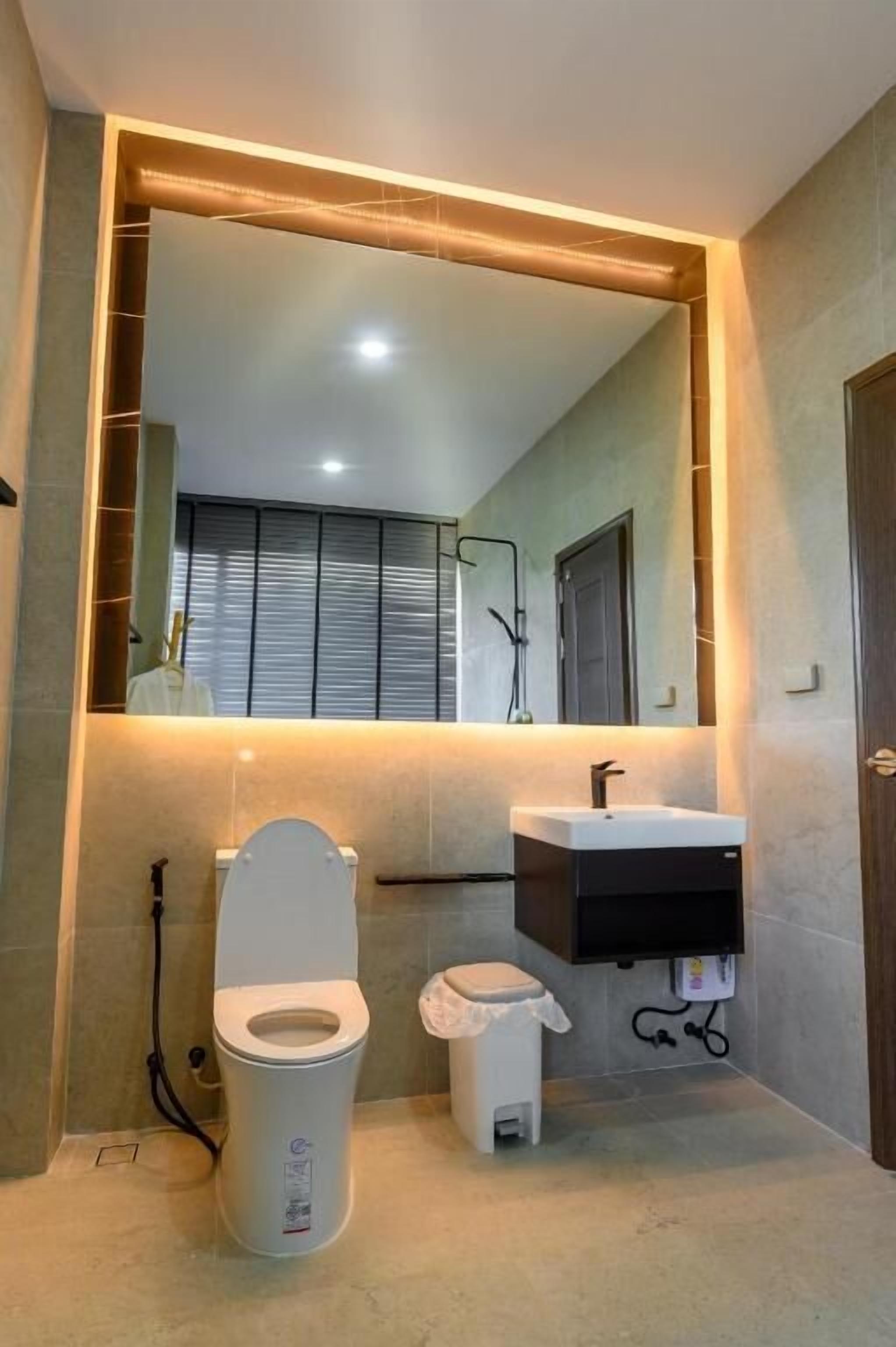 A modern bathroom with a toilet, sink, and mirror.