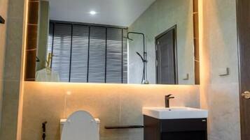 A modern bathroom with a toilet, sink, and mirror.