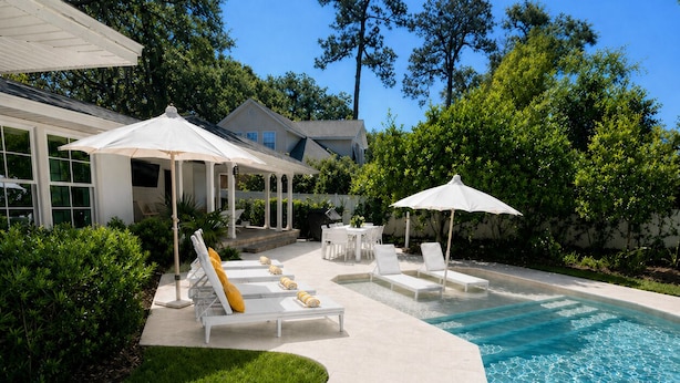A poolside area with lounge chairs, umbrellas, and a clear blue pool. - The Maggie Mae: Stylish Retreat | Private Pool + Walk to the Best of St. Simons (Saint Simons Island)