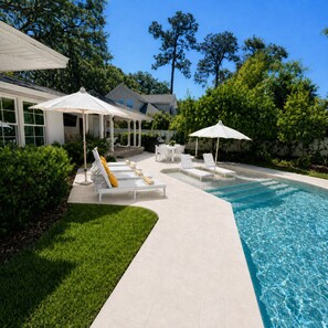 A poolside area with lounge chairs, umbrellas, and a clear blue pool. - The Maggie Mae: Stylish Retreat | Private Pool + Walk to the Best of St. Simons (Saint Simons Island)
