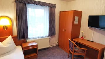 Una habitación de hotel con cama, escritorio, silla, televisión y armario.