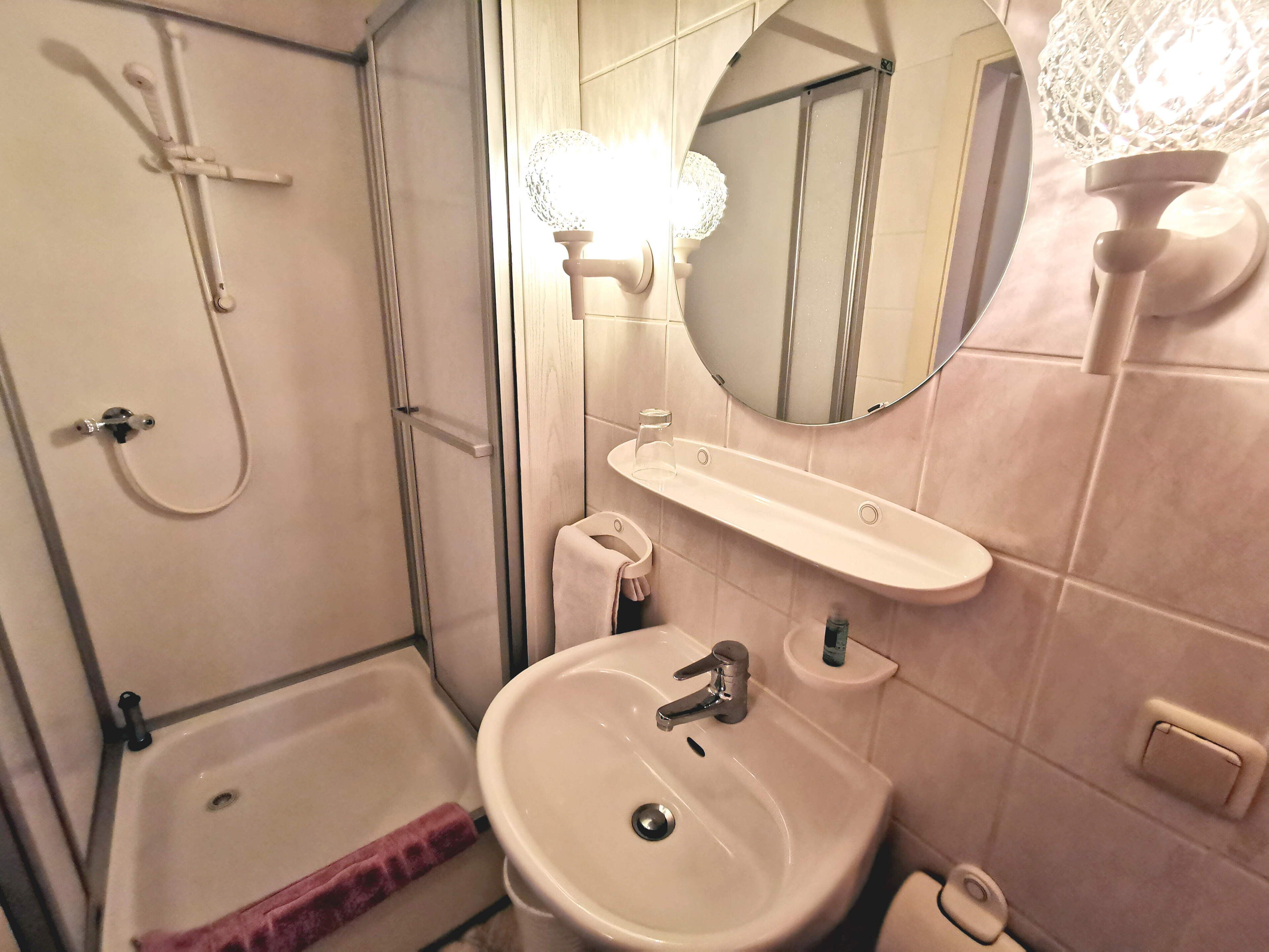 Un bany amb banyera, un lavabo, un mirall i una dutxa.