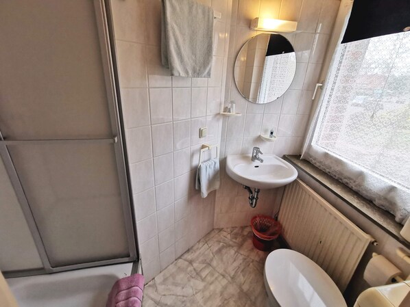 A bathroom with a sink, mirror, towel rack, and a window.