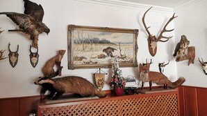 Una habitación con un aparador de madera que exhibe varias cabezas de animales y un cuadro enmarco de una escena de caza.