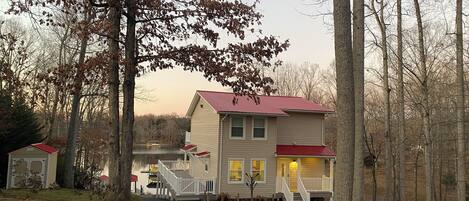 A two-story house with a red roof, a front porch, and a staircase leading to the entrance.