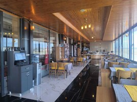 Un restaurante moderno con una barra larga, techo de madera y grandes ventanales con vistas.