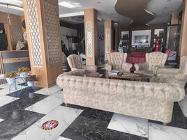 Un vestíbulo con un lujoso conjunto de sofás, suelo de mármol y una mesa de recepción.