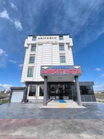 Un edificio de varios pisos con un cartel que dice 'ARIFOGLU AIRPORT HOTEL'.