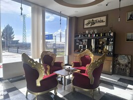 Una habitación con dos sillones rojos ornamentados, una mesita y una zona de bar con diversos objetos.