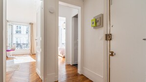 A hallway with wooden flooring, white walls, and a door with a light switch.