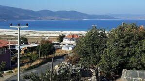 A coastal view with a clear sky, a beach, and a residential area with houses and a road. - Tan Apart Aile Ev Pansiyonu (Yesilova)