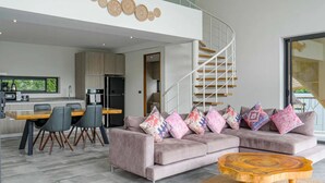 Ein modernes Wohnzimmer mit Sofa, Couchtisch und Essbereich mit Stühlen und Tisch.