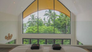 Ein Schlafzimmer mit großem Fenster, einem Bett und einem Deckenventilator.