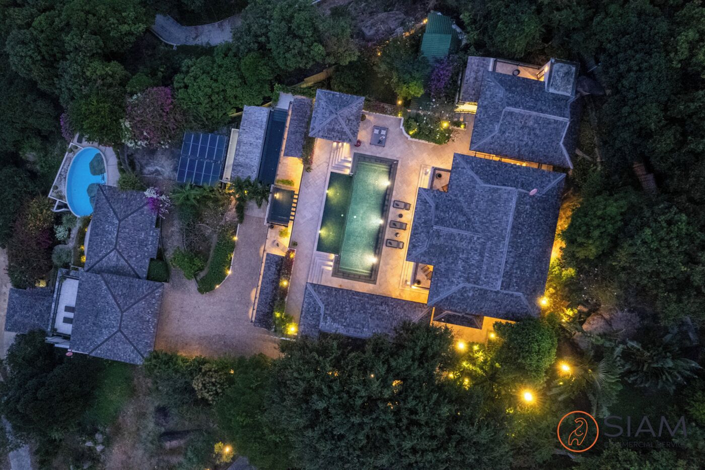 An aerial view of a residential property with a swimming pool, multiple rooms, and a well-lit outdoor area.