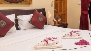 Une chambre d’hôtel avec un lit, des oreillers, un élément décoratif mural, une porte en bois et un rideau rouge.