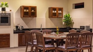 Une cuisine moderne avec des meubles en bois, un four encastré et un coin repas comprenant une table et des chaises.