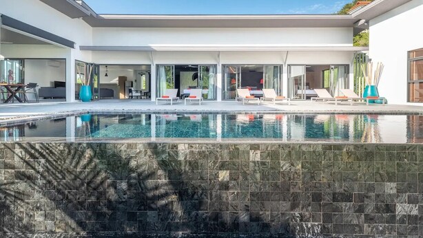 A modern house with a swimming pool, outdoor seating, and large windows. - Elegant 4-bedroom villa with private pool, waterfall showers, and garden (Tambon Mae Nam)