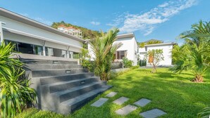 A modern house with a well-maintained lawn, a set of concrete steps leading to the entrance, and a clear blue sky. - Elegant 4-bedroom villa with private pool, waterfall showers, and garden (Tambon Mae Nam)