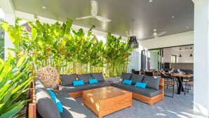 A modern living area with a sectional sofa, a wooden coffee table, and a dining table. - Elegant 4-bedroom villa with private pool, waterfall showers, and garden (Tambon Mae Nam)