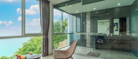A modern room with a large window, a dining area with a table and chairs, and a kitchen area with a tiled backsplash.