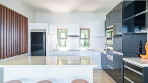 Une cuisine moderne dotée d’un îlot central, de meubles blancs et d’un mur d’accent en bois.