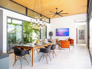 A modern dining area with a wooden table, black chairs, and a large window overlooking greenery.