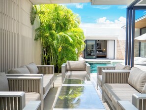 Un espace de détente extérieur moderne, doté d’une piscine, de sièges et d’une végétation luxuriante.