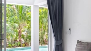 A hotel room with a bed, a view of a swimming pool, and a curtain.