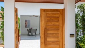 A wooden door leading to a covered outdoor area with a table and chairs.