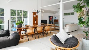 A spacious living area with a dining table, chairs, a sofa, and a ceiling fan.
