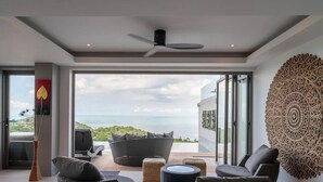 Una sala de estar moderna con un ventanal grande, un ventilador de techo y un adorno de pared.