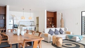 A modern kitchen with wooden cabinets, a dining table with chairs, and pendant lighting.