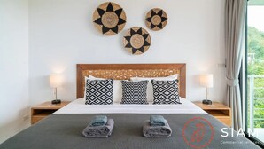 A hotel room with a bed, two bedside tables, patterned pillows, and wall decor.