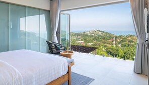 A bedroom with a large bed, a ceiling fan, and a view of a hilly landscape through a glass door. - Luxurious 3 king-suite villa in Plai Laem Soi 8 with private pool, sea views, and WiFi (Koh Samui)