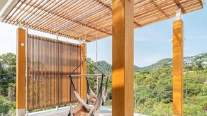 Eine Holz-Pergola mit einer Hängematte und Blick auf eine üppige, grüne Landschaft.