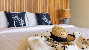 A neatly made bed with a striped bedspread, two pillows with palm tree designs, a straw hat, and a woven basket on the bed. - Stunning 3-bedroom villa in Chaweng with private pool and sea views, near beach (Koh Samui)