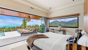 A modern bedroom with a large bed, a desk, and a view of the ocean and mountains. - Stunning 3-bedroom villa in Chaweng with private pool and sea views, near beach (Koh Samui)