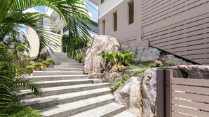 A set of stone steps leading up to a building with a wooden gate, surrounded by rocks and greenery. - Stunning 3-bedroom villa in Chaweng with private pool and sea views, near beach (Koh Samui)