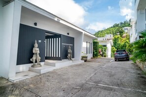 A modern house with a white exterior, a dark entrance, and a car parked in the driveway.