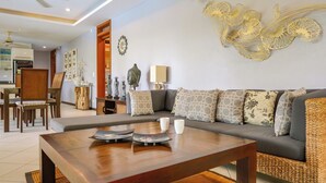 Un salon moderne avec une table basse en bois, un canapé gris agrémenté de coussins à motifs et un élément décoratif mural.