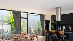 A modern kitchen with a large island, dark cabinetry, and a stainless steel range hood. - Modern 2-bedroom oasis with private pool, garden, and dedicated workspace, ideal for families (Tambon Mae Nam)